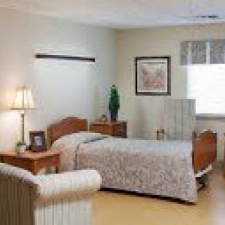 A cozy and neatly arranged hospital room with a single bed and soft lighting.