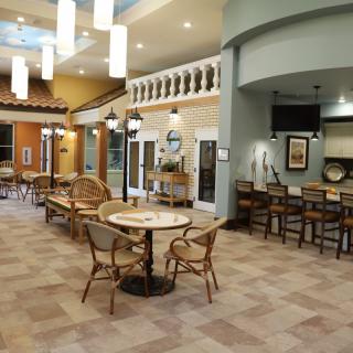 A cozy restaurant interior with tables and chairs arranged under warm lighting.