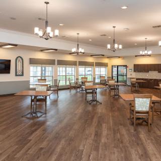 A spacious and well-lit dining area featuring wooden tables and chairs, ideal for community gatherings.