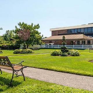 A serene garden with a bench and a pathway leading to a building.