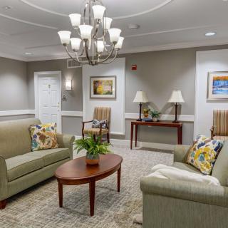 A cozy and elegantly decorated living room featuring comfortable sofas, a wooden coffee table, and a chandelier.