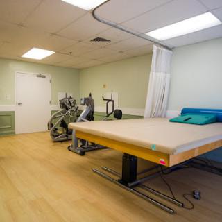 A spacious therapy room equipped with exercise equipment and a treatment bed.