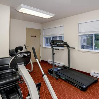 A small gym with a treadmill and stationary bikes.