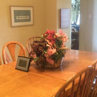 A cozy dining room setup with a wooden table, chairs, and a decorative flower arrangement centerpiece.