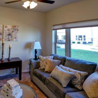 A cozy living room with a comfortable sofa and large windows overlooking the backyard.