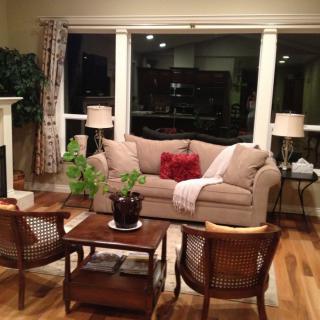 A cozy living room with a beige sofa, two wooden chairs, a coffee table, and decorative lamps.