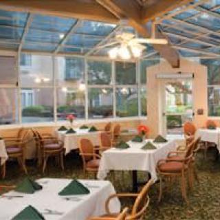 A cozy dining area with tables set for a meal, featuring ample natural light from the glass ceiling.