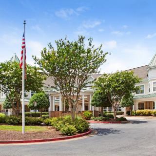 A view of a large building with an American flag and landscaped gardens at the entrance.