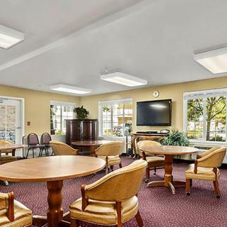A spacious and well-lit meeting room with tables, chairs, and a television.