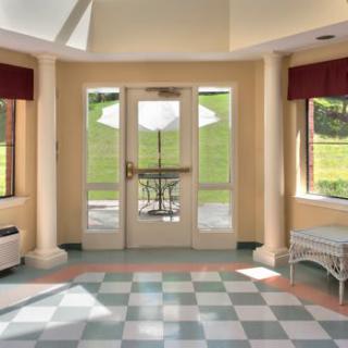 A bright entrance with large windows, a checkered floor, and decorative columns.