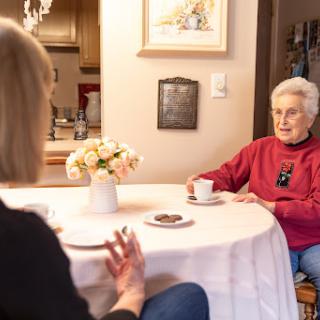Two women engage in a warm conversation over coffee in a cozy home setting.