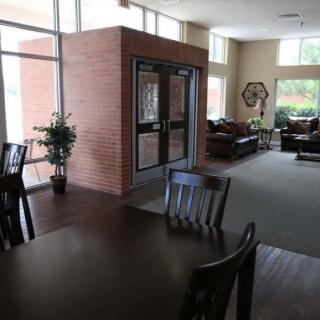 A well-lit lobby area featuring tables, chairs, sofas, and a brick wall.