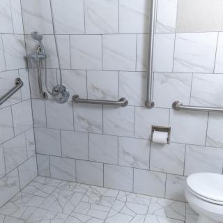 An accessible bathroom featuring grab bars and a tiled interior.