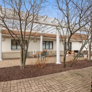 A peaceful patio area with a pergola and outdoor seating surrounded by trees.