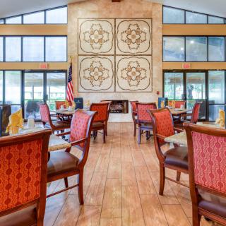 A well-lit dining area with red cushioned chairs, tables set for service, and large decorative wall art.