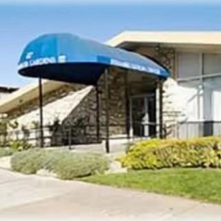 A building entrance with a blue awning and landscaped surroundings.