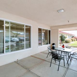 A cozy outdoor patio area with a table and chairs, surrounded by large windows, perfect for relaxation.