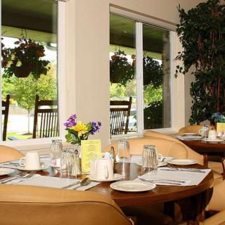 A cozy restaurant interior with neatly set tables and floral decorations by the window.