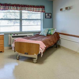 A clean, organized hospital room featuring a single bed by the window.