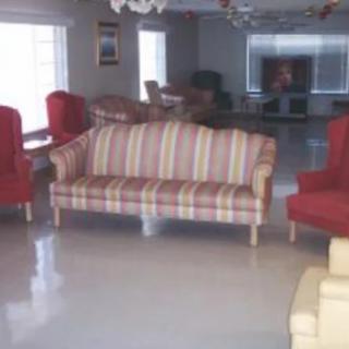 A spacious living room with a variety of seating options including a striped sofa and red chairs.