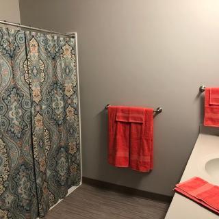 A bathroom featuring a colorful shower curtain and matching red towels.
