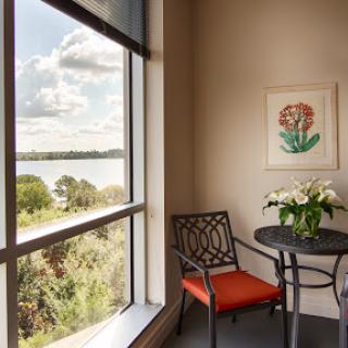 A cozy corner with a view of nature, featuring a small table and chair adorned with fresh flowers.
