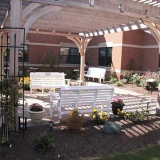A serene outdoor seating area with benches under a pergola, surrounded by flowers.