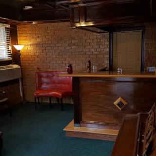 A cozy retro-style bar with wooden furniture and brick walls, featuring a small seating area.
