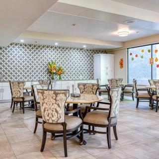 A modern dining area with decorative wallpaper, stylish chairs, and bright lighting.
