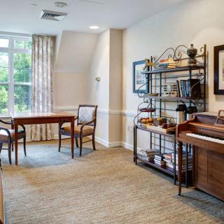 A well-lit living room with a table, chairs, and decorative shelving.