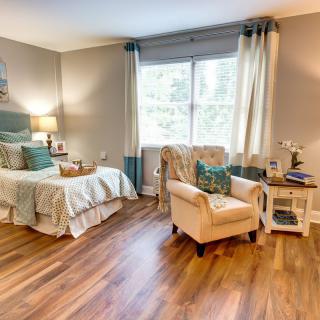 A cozy bedroom with stylish furnishings and natural light streaming through a large window.