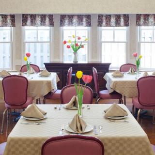 A brightly lit dining room with neatly arranged tables and floral centerpieces.