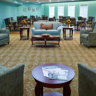 A well-furnished lounge area with sofas, chairs, and tables arranged on a patterned carpet.