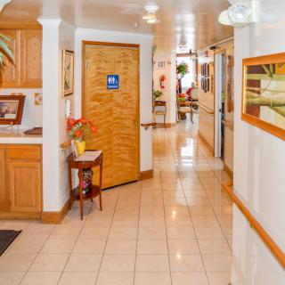 A well-decorated hallway with tile flooring, featuring a wooden door and decorative elements such as plants and paintings.