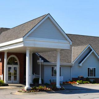 A modern building with a prominent entrance featuring pillars and a gabled roof.