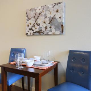 Cozy dining area with blue chairs and a floral painting.
