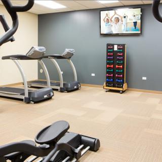 A clean and modern gym space equipped with treadmills, weights, and exercise machines.