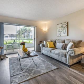 A modern living room with a comfortable sofa, coffee table, and bright natural light coming through a sliding glass door.