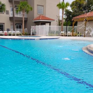 A serene outdoor swimming pool surrounded by palm trees and resort buildings.
