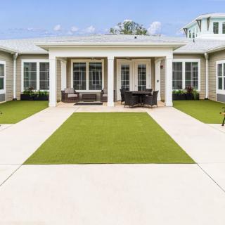 A spacious courtyard with a lawn and outdoor seating in front of a modern house.