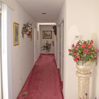 A carpeted hallway adorned with floral arrangements and paintings.