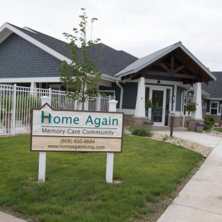 A memory care facility named 'Home Again' with a well-maintained exterior and signage.