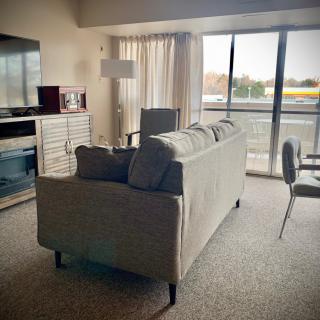 A cozy living room with a sofa, lamp, and large window.