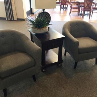 A cozy seating arrangement featuring two armchairs and a side table with a lamp and plant.