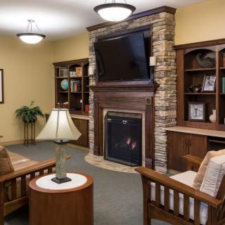 A cozy living room with a fireplace, television, and built-in bookshelves.
