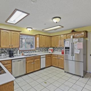A spacious kitchen with wooden cabinets, stainless steel appliances, and a tiled floor.