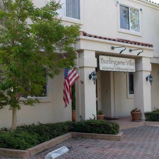 The entrance of a building with an American flag and potted plants.
