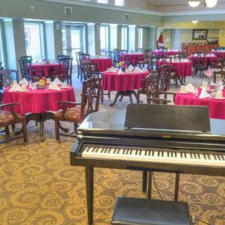 A dining area with neatly arranged tables and a piano in the foreground.