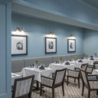 Elegant dining area with neatly arranged tables and framed artwork on the walls.