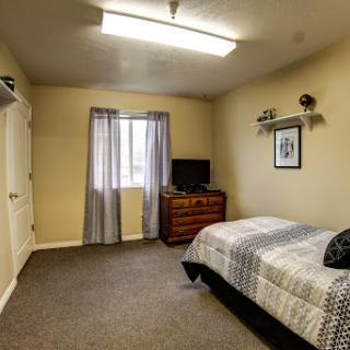 A cozy bedroom featuring a bed, a dresser, and a television.